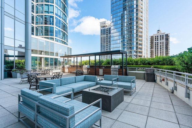 view of patio / terrace with grilling area, a view of city, an outdoor living space with a fire pit, and exterior kitchen