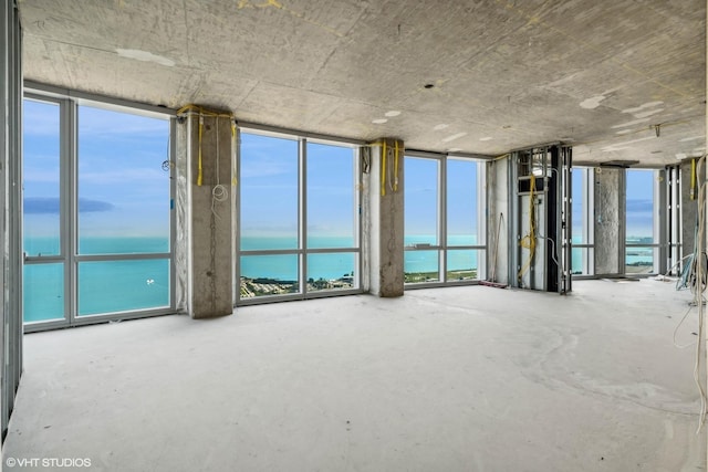 unfurnished room featuring concrete floors and a water view