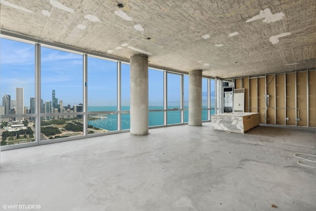 unfurnished living room featuring a view of city, floor to ceiling windows, a water view, and concrete floors