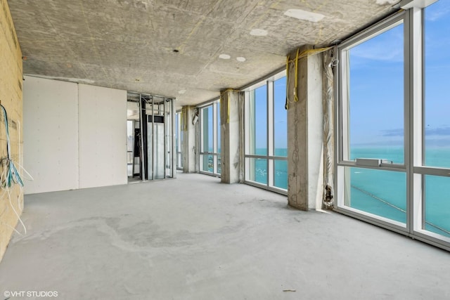 spare room with a water view and concrete floors