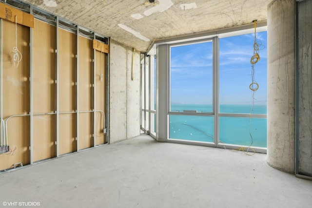 spare room featuring a water view and concrete floors