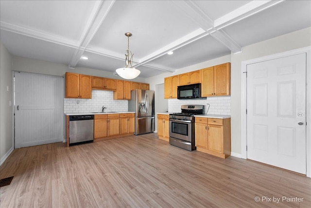 kitchen featuring light wood-type flooring, decorative light fixtures, tasteful backsplash, stainless steel appliances, and light countertops