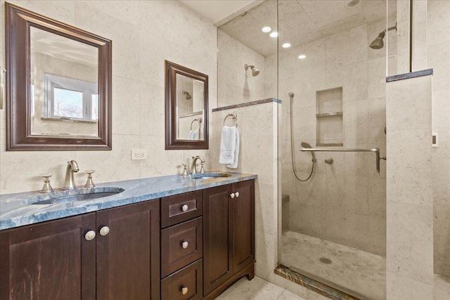 bathroom featuring double vanity, a stall shower, and a sink