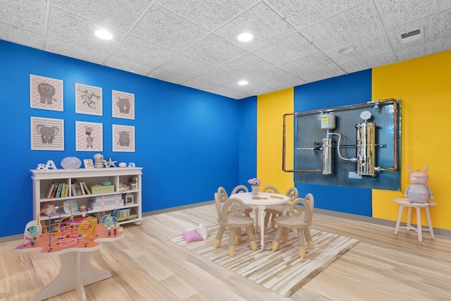 playroom featuring visible vents, a paneled ceiling, baseboards, and wood finished floors