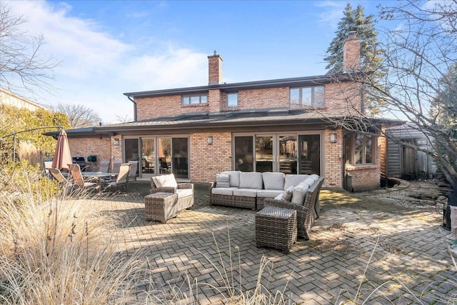 rear view of house with a patio, a chimney, brick siding, and an outdoor living space