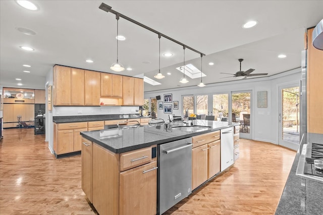 kitchen with light wood-type flooring, stainless steel appliances, a kitchen island with sink, and light brown cabinets