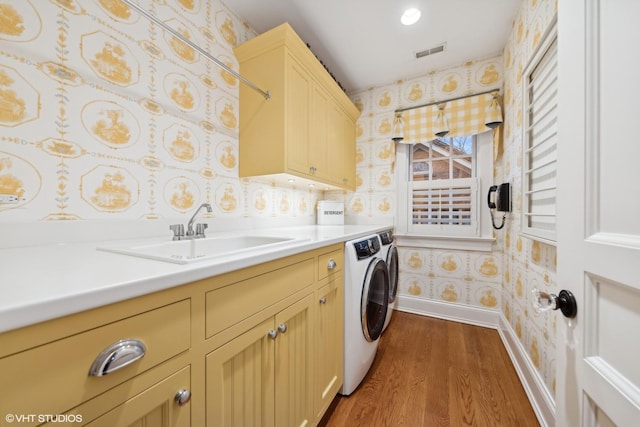 laundry room with visible vents, independent washer and dryer, a sink, cabinet space, and wallpapered walls