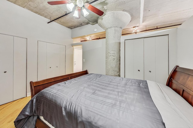 bedroom featuring multiple closets, wood finished floors, and a ceiling fan