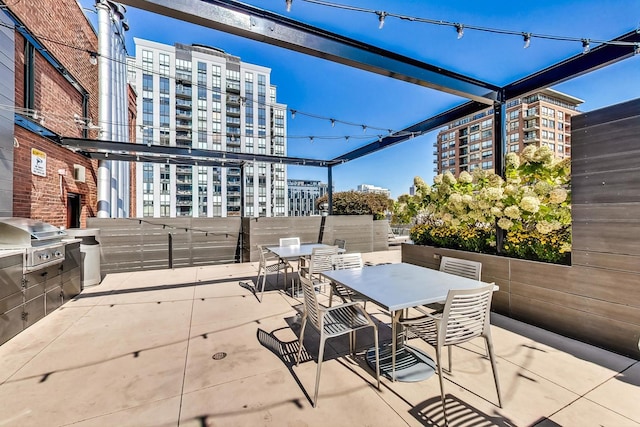 view of patio / terrace featuring a city view, outdoor dining area, a grill, and exterior kitchen