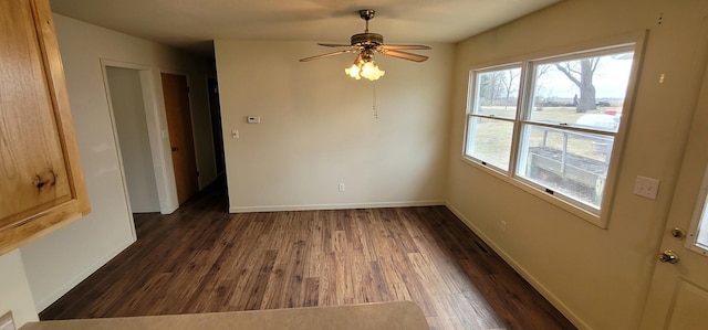 empty room featuring a ceiling fan, dark wood-type flooring, and baseboards