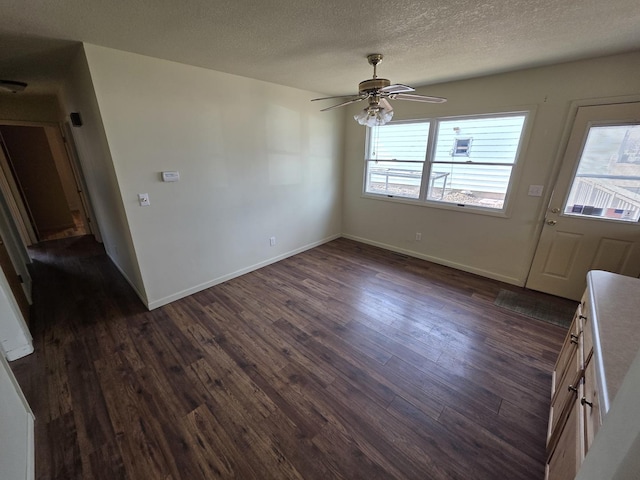 interior space featuring baseboards, a textured ceiling, ceiling fan, and dark wood-style flooring