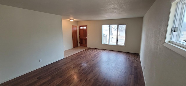 unfurnished room with baseboards, dark wood-style flooring, and a textured ceiling