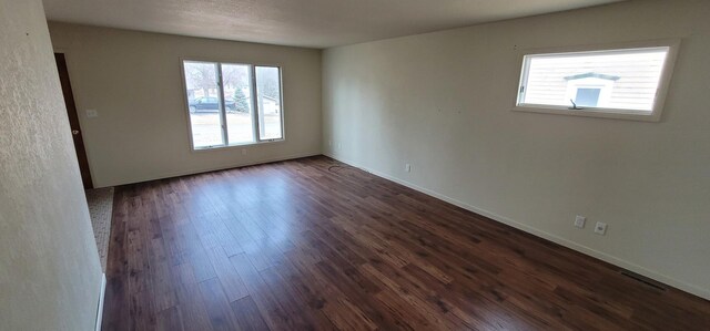 spare room featuring dark wood-style floors and baseboards