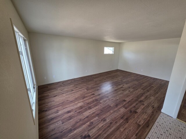 unfurnished room with dark wood finished floors and a textured ceiling