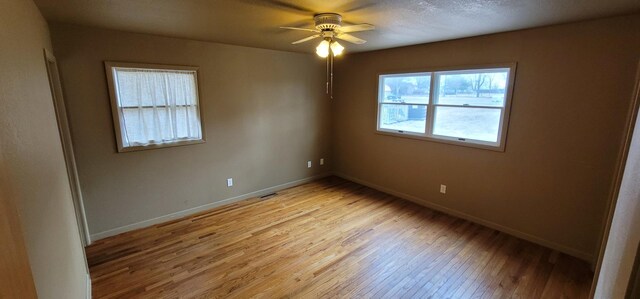 spare room with light wood finished floors, visible vents, a ceiling fan, and baseboards