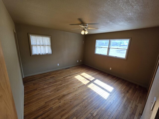 unfurnished room with a textured ceiling, a ceiling fan, baseboards, and hardwood / wood-style flooring