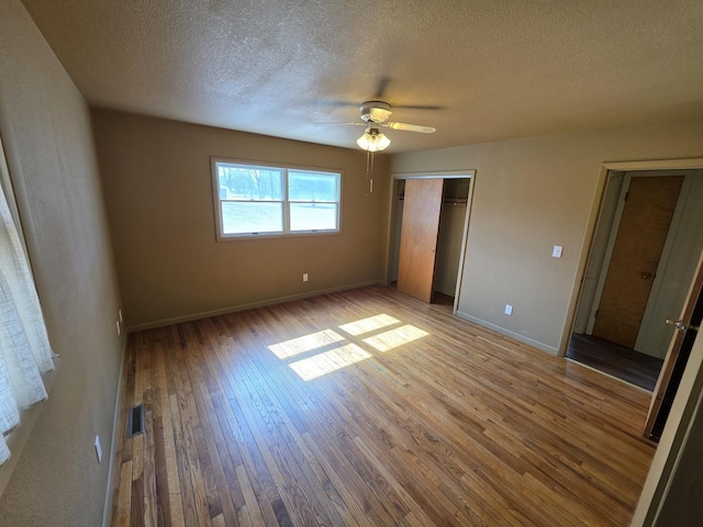 unfurnished bedroom with baseboards, visible vents, a closet, wood-type flooring, and a textured ceiling