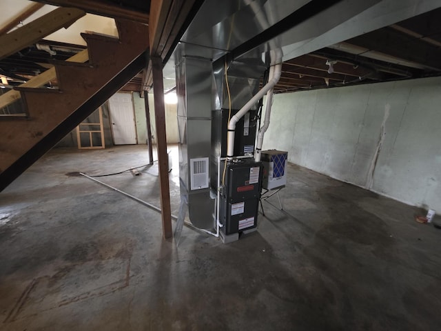 unfinished basement featuring stairway and heating unit