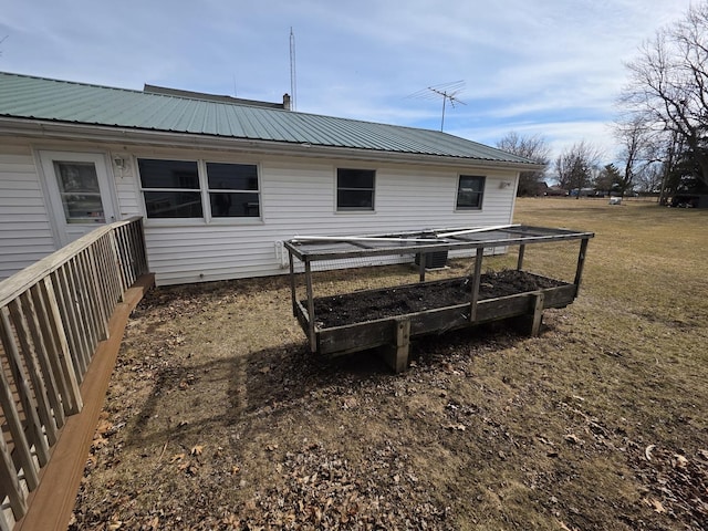 rear view of property featuring metal roof and a vegetable garden