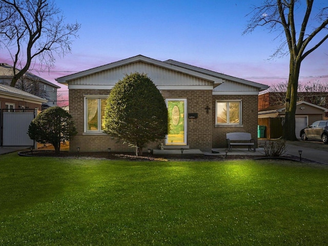 view of front of house featuring a patio area, brick siding, a front lawn, and fence