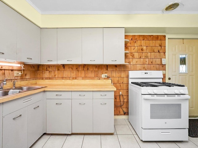 kitchen with white range with gas cooktop, light tile patterned flooring, a sink, light countertops, and crown molding