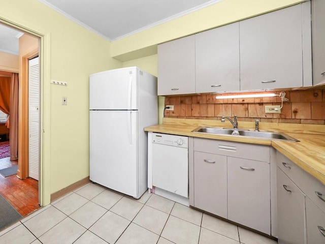 kitchen with decorative backsplash, white appliances, a sink, and ornamental molding