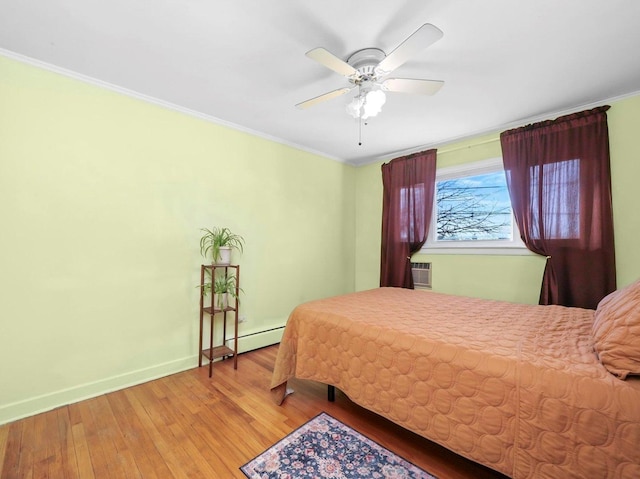 bedroom with a baseboard heating unit, hardwood / wood-style floors, crown molding, baseboards, and ceiling fan
