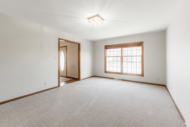 spare room with visible vents, light colored carpet, and baseboards