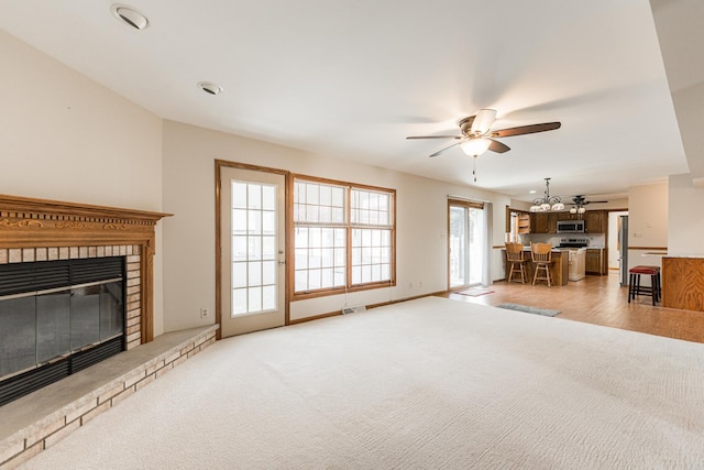 unfurnished living room with light carpet, visible vents, a fireplace, and ceiling fan