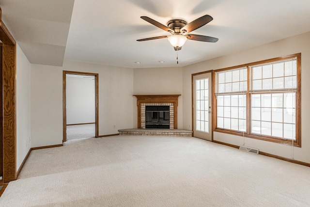 unfurnished living room featuring visible vents, light carpet, a fireplace, baseboards, and ceiling fan