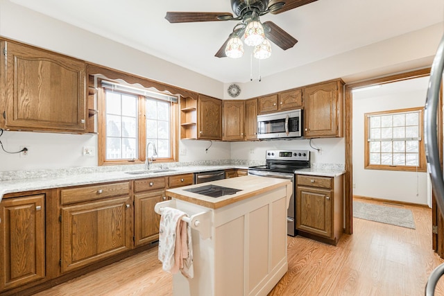 kitchen with a sink, plenty of natural light, light wood-style floors, and stainless steel appliances