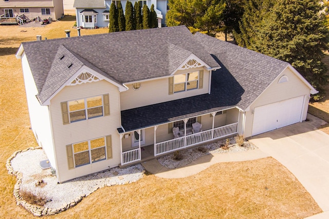 view of front of home with concrete driveway, a garage, covered porch, and a shingled roof