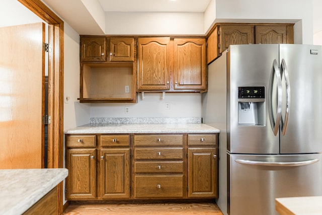 kitchen with light countertops, brown cabinetry, and stainless steel refrigerator with ice dispenser