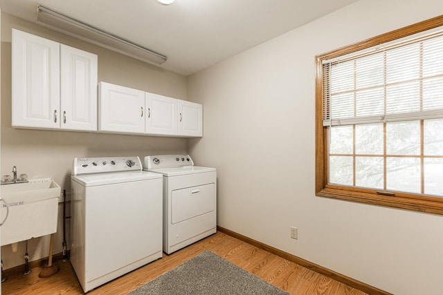 laundry room featuring baseboards, cabinet space, washing machine and dryer, and light wood finished floors