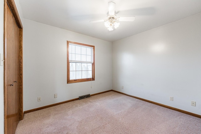 spare room with light colored carpet, visible vents, and baseboards