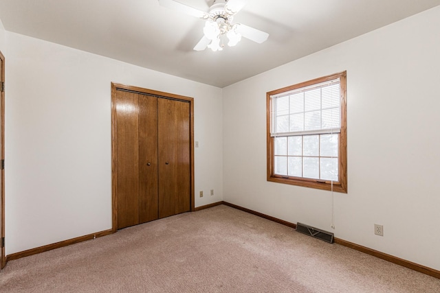 unfurnished bedroom with a closet, visible vents, light colored carpet, and baseboards