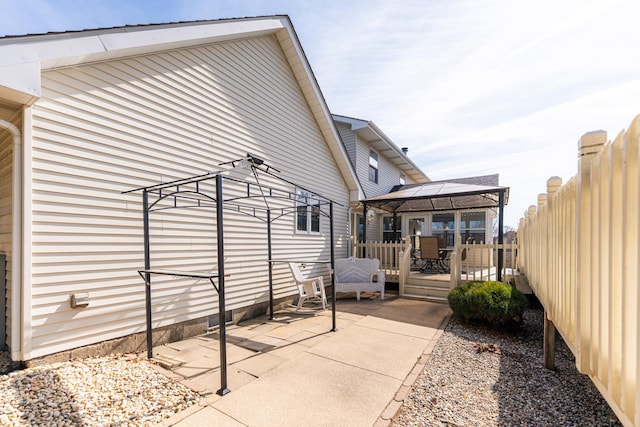 view of property exterior with a gazebo, a wooden deck, and fence