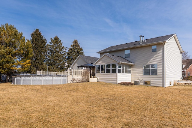 back of property with a covered pool, central air condition unit, a lawn, and a sunroom