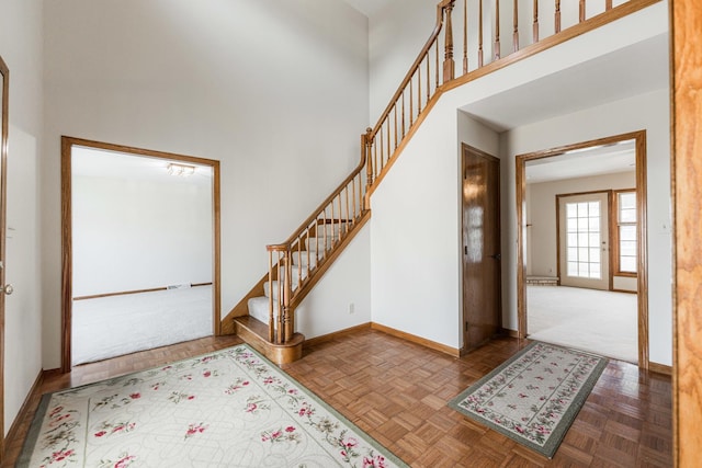 entrance foyer with baseboards, a high ceiling, and stairs