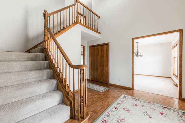 foyer featuring a notable chandelier, stairs, a high ceiling, and baseboards