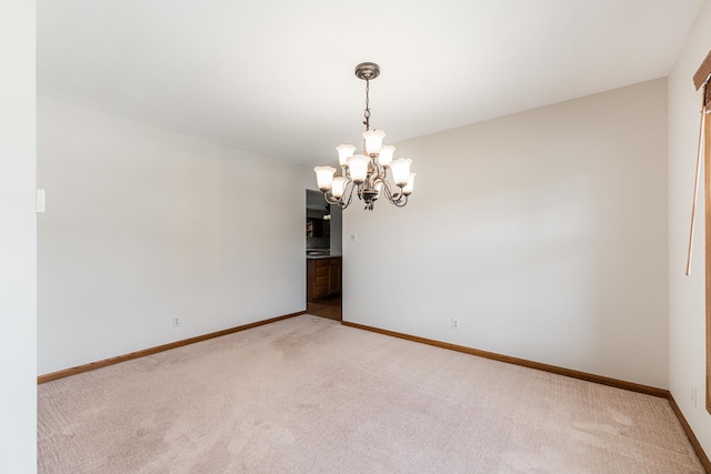 unfurnished room with baseboards, a notable chandelier, and carpet flooring