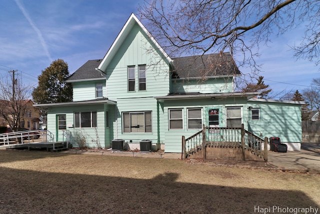 rear view of property with cooling unit and roof with shingles