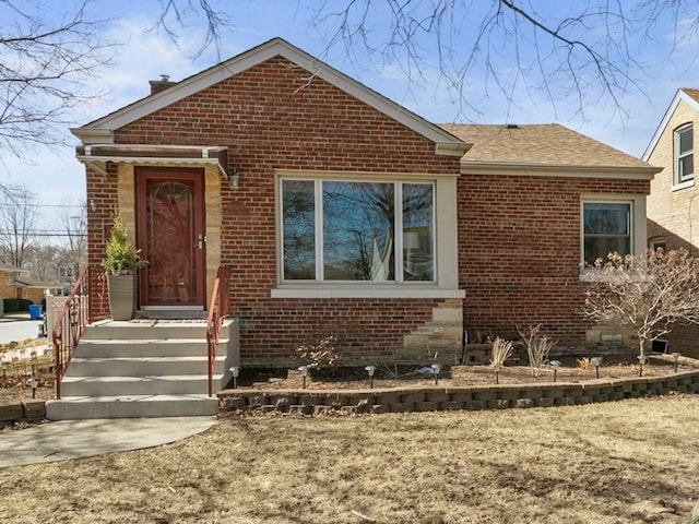 view of front of home featuring brick siding and roof with shingles