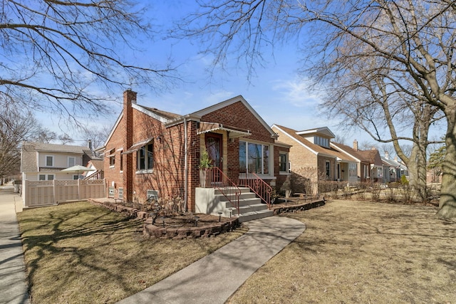 view of front of house featuring brick siding, a residential view, a chimney, and fence