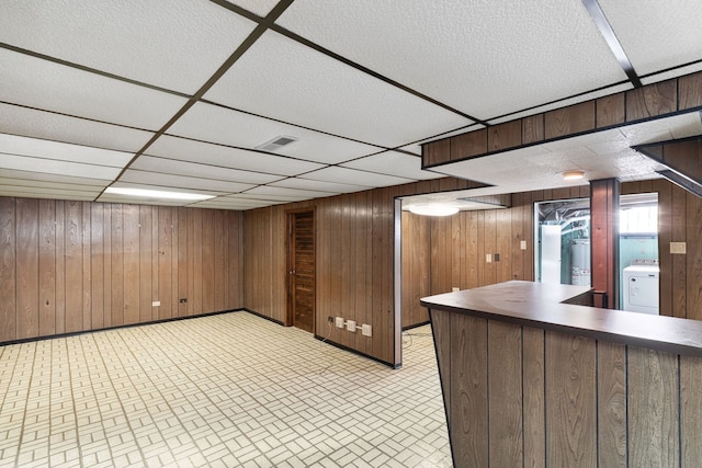 bar with a drop ceiling, wood walls, washer / clothes dryer, and visible vents