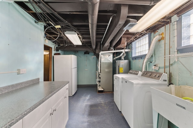 laundry area featuring a sink, heating unit, electric water heater, cabinet space, and separate washer and dryer