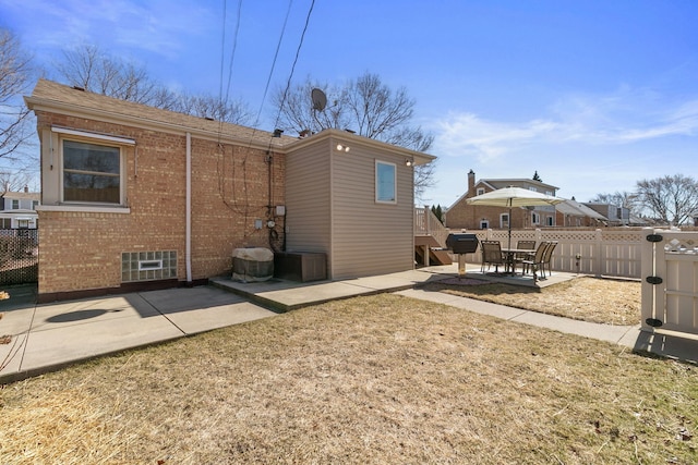 rear view of house with a patio, brick siding, and fence