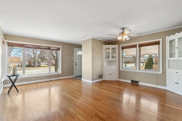 unfurnished living room with baseboards, visible vents, light wood finished floors, ceiling fan, and crown molding