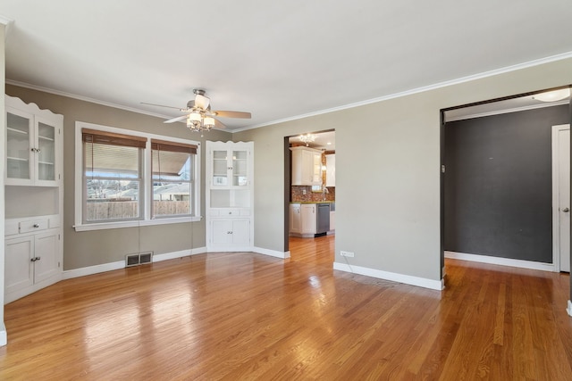 unfurnished dining area with a ceiling fan, crown molding, light wood-style floors, and visible vents