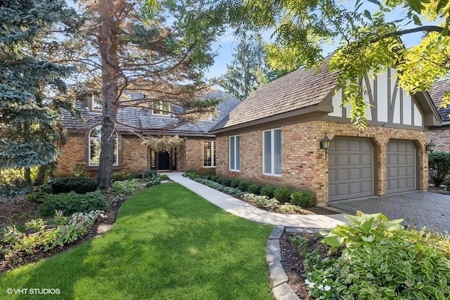 exterior space featuring decorative driveway, a front yard, an attached garage, and brick siding